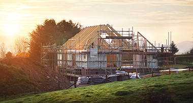 a new build house with scaffolding around it in the countryside 