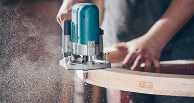 a carpenter using a planer to prepare a piece of wood for use in a project