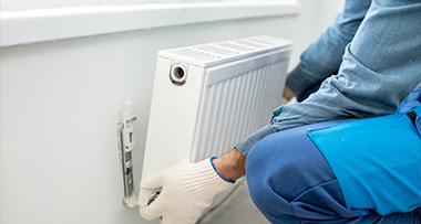 a person installing a wall-mounted radiator as a part of a heating system in a home