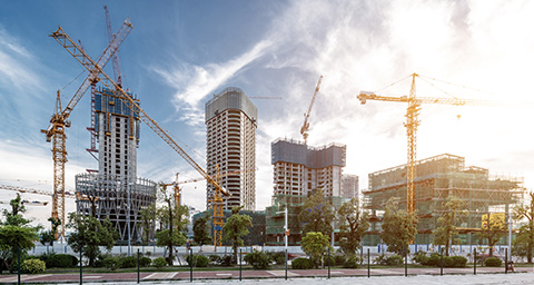 different commercial buildings with cranes around them in the distance