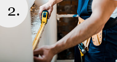 a builder measuring a window sill with a yellow measuring tape